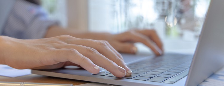 Hands typing on a laptop keyboard