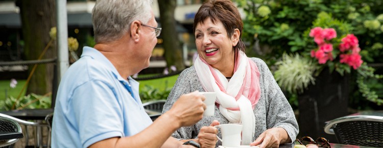 An older couple enjoying a cup of coffee outside at a café.