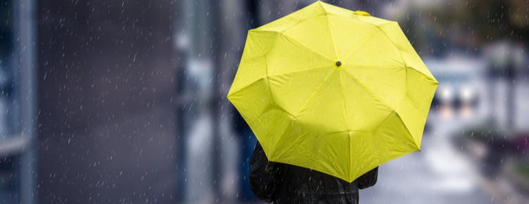 A person holding a yellow umbrella as they walk down a street