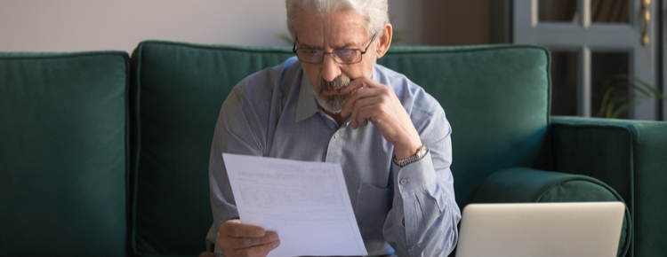 An older man reviewing some paperwork at home.