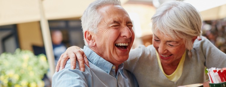 A retired couple laughing at a café.