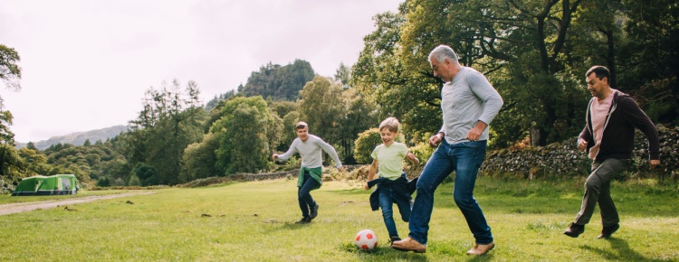 Multi-generational family playing football in a park.