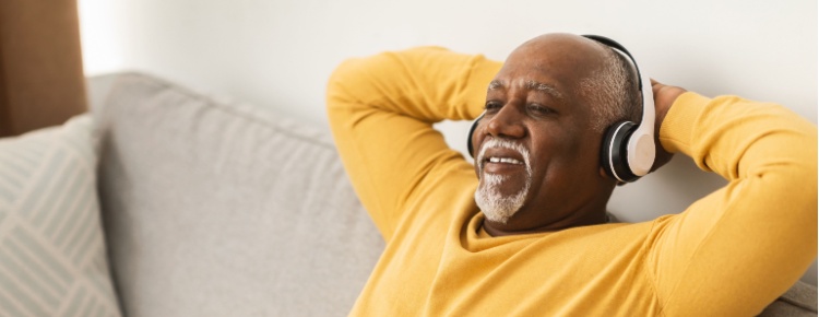 A man relaxing on a sofa with his hands behind his head.