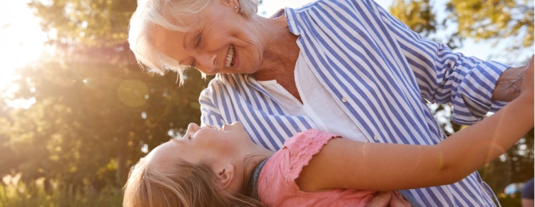 A grandmother playing with her granddaughter outside.