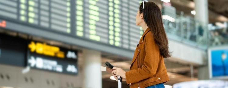 A woman looking at a departure board in an airport.